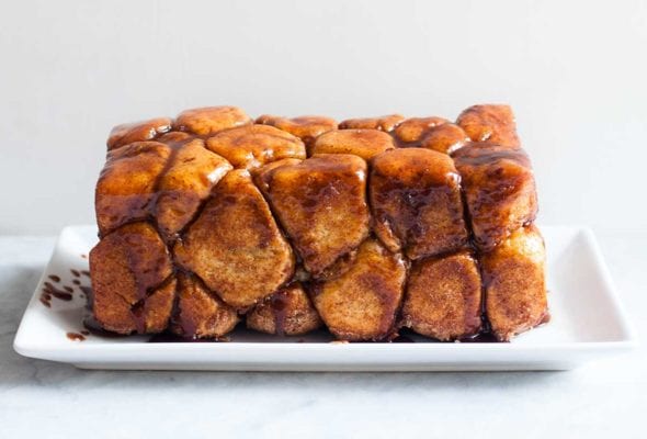 A loaf of monkey bread--balls of caramel-coated bread dough dripping caramel sauce on a rectangle plate