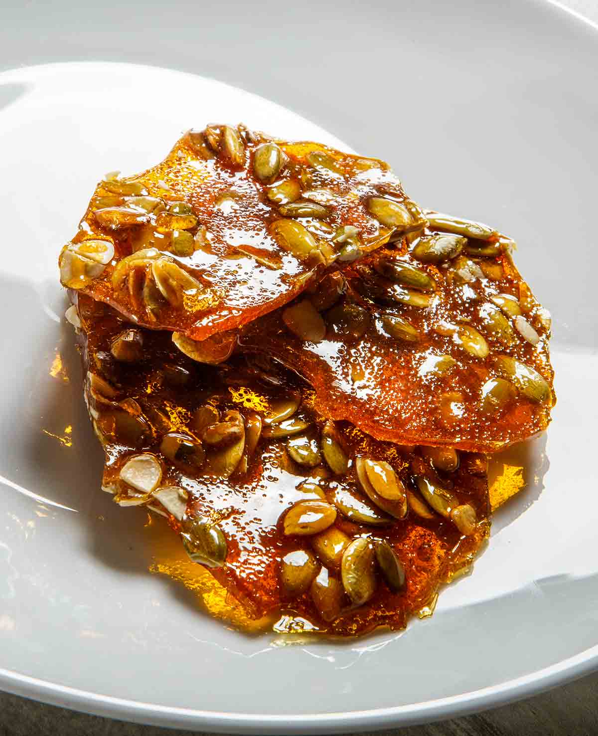 A white plate with three pieces of spicy pepita brittle on it