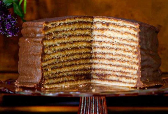 Trisha Yearwood's chocolate torte on a cake stand with a section cut from it to display 12 layers.