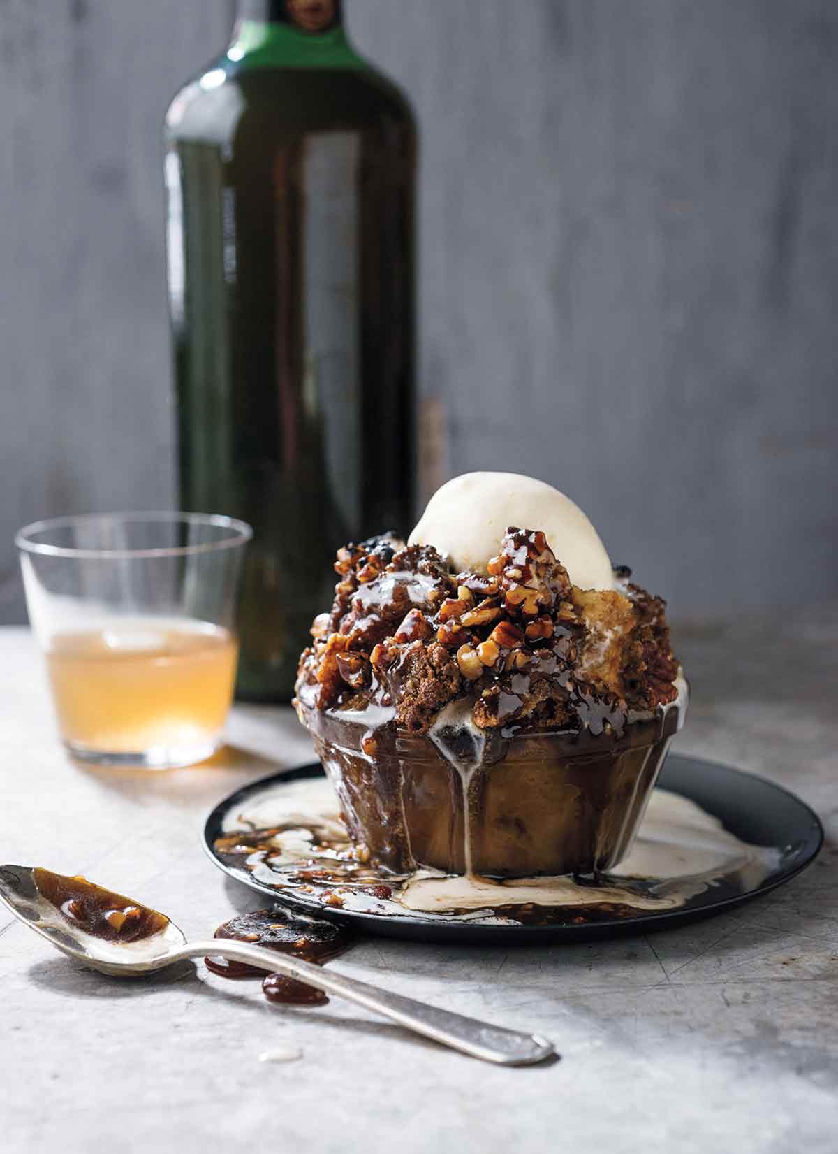 Glass bowl filled with pecan pie bread pudding, caramel sauce, bourbon-vanilla ice cream on a marble table