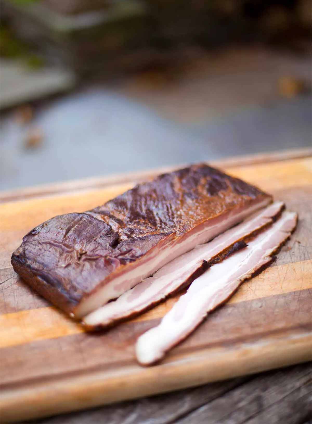 Homemade maple-espresso bacon on a cutting board on a stone slab