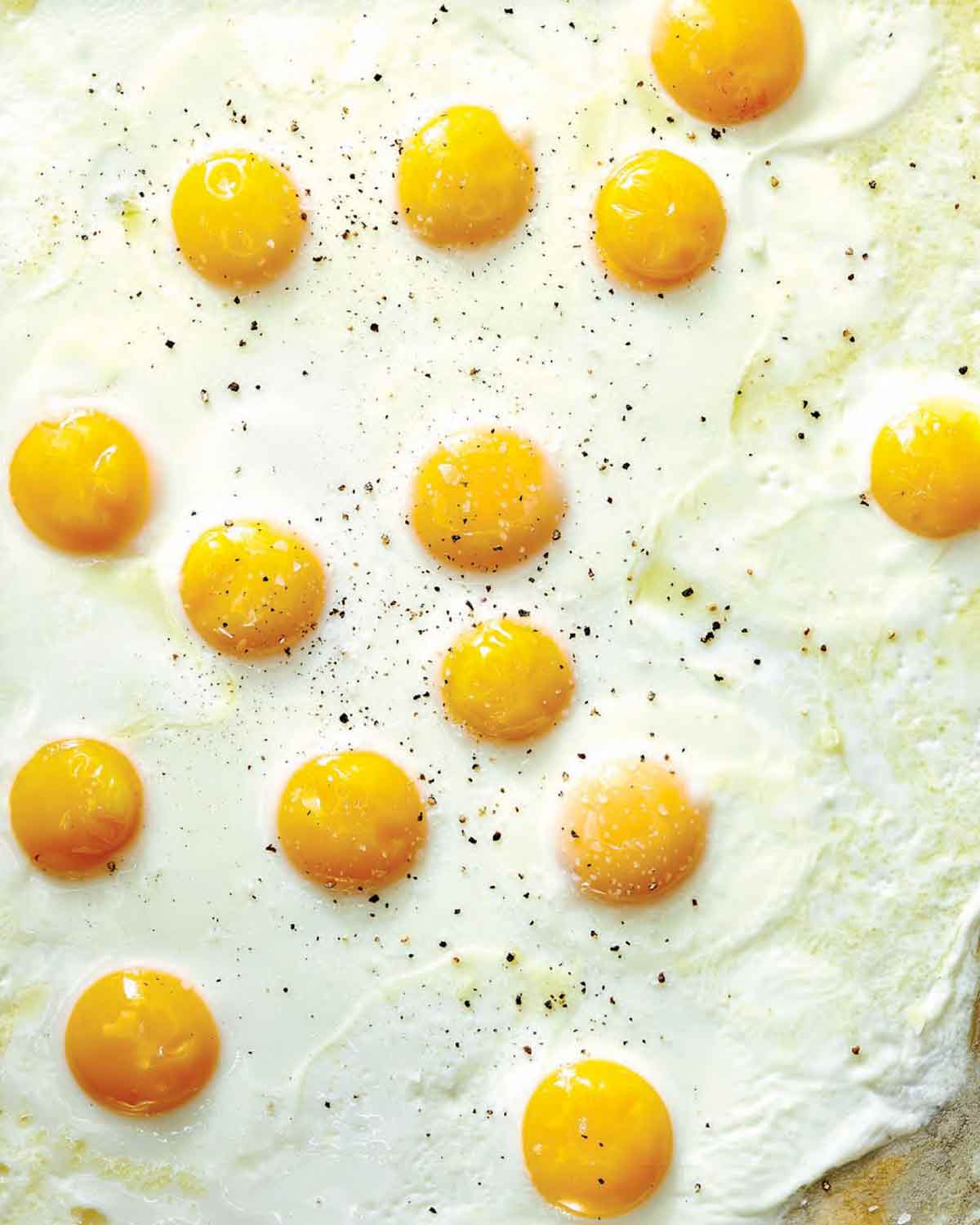 Sunny side up sheet pan eggs on a baking sheet.