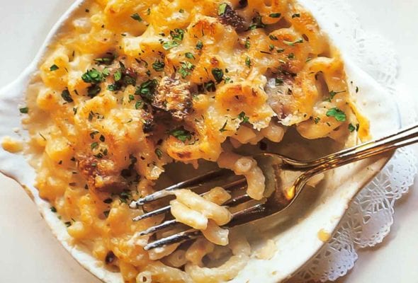 A white dish of macaroni gratin with a fork resting inside.