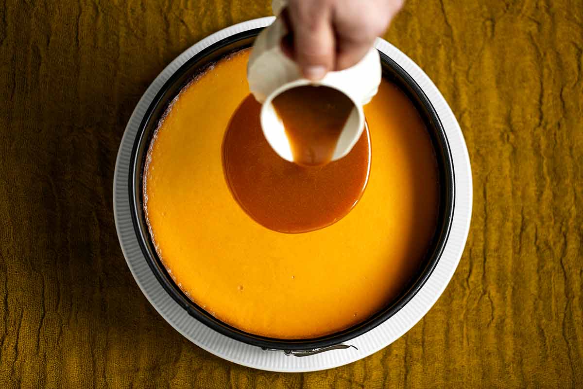 A pure pumpkin cheesecake on a white plate drizzled with caramel glaze.