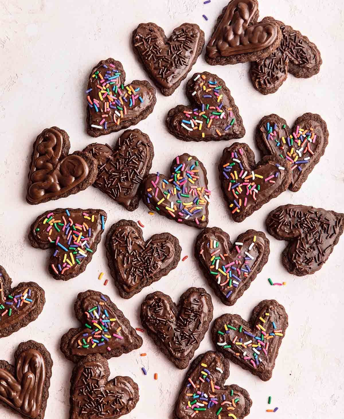 Heart shaped vegan gluten-free chocolate sugar cookies decorated with sprinkles.