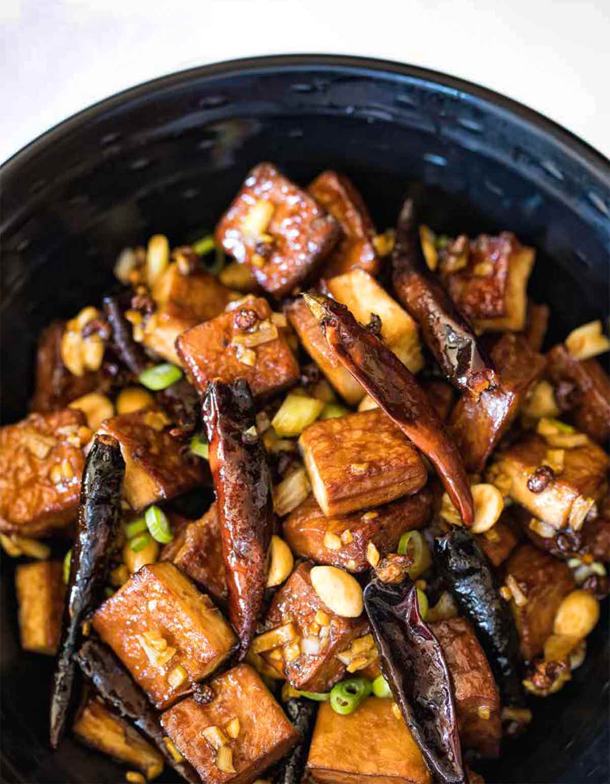 A black dish filled with spicy tofu with peanuts.