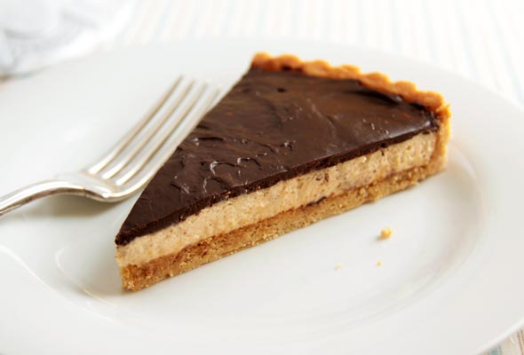 A slice of chocolate peanut butter tart with a cookie crust, peanut butter mousse filing, and a chocolate ganache topping